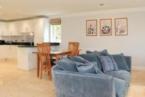 ein Wohnzimmer mit einer blauen Couch und einer Küche in der Unterkunft BEACHSIDE SPACIOUS apartment, private garden in Saint Merryn