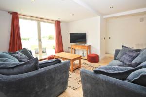 ein Wohnzimmer mit zwei Sofas und einem Fernseher in der Unterkunft BEACHSIDE SPACIOUS apartment, private garden in Saint Merryn