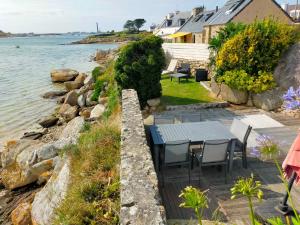 a patio with a table and chairs next to the water at Kelerdut Plage in Plouguerneau