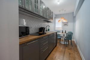 eine Küche mit grauen Schränken und einem Tisch mit Stühlen in der Unterkunft Boutique Luxury Apartment - Alhambra in Bukarest