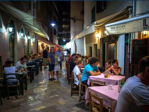 a group of people sitting at tables in an alley at Apartments Anna in Zadar