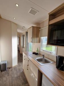 a small kitchen with a sink and a window at Summer Breeze Getaway, West Sands in Selsey