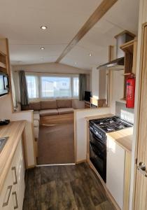 a kitchen with a stove and a couch in a caravan at Summer Breeze Getaway, West Sands in Selsey