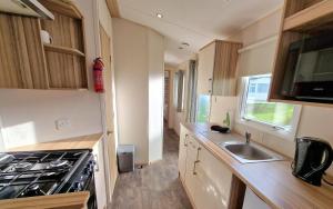 a small kitchen with a sink and a stove at Summer Breeze Getaway, West Sands in Selsey