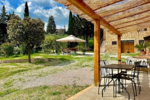 a patio with a table and chairs and an umbrella at Podere Casa Rossa a Pienza in Pienza