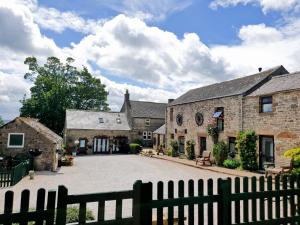 an old stone house with a fence in front of it at Bolehill Farm Cottages in Bakewell