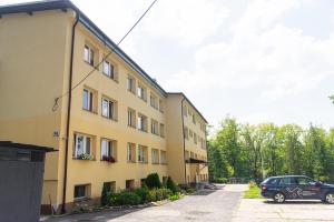 samochód zaparkowany przed żółtym budynkiem w obiekcie Apartament Parkowy Rabka w Rabce