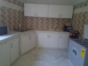a kitchen with white cabinets and a tile floor at Keur Fatou in Ngaparou