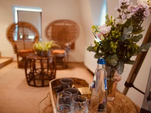 a table with glasses and a bottle and flowers on it at L'Amarante chambres d'hôtes OU gîte citadin in Theux