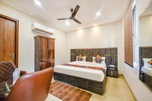 a bedroom with a king sized bed and a chair at FabHotel Globe Inn in Ludhiana