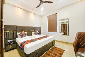 a bedroom with a large bed and a chair at FabHotel Globe Inn in Ludhiana
