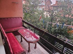 a red bench and a table on a balcony at Apartmani,,Drljaca,,1 in Soko Banja