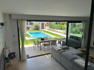 ein Wohnzimmer mit einem Sofa, einem Tisch und einem Pool in der Unterkunft Luxury house in Puerto Alcudia in Alcúdia