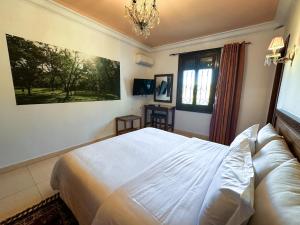 a bedroom with a white bed and a chandelier at Riad Dar Achaach in Tétouan