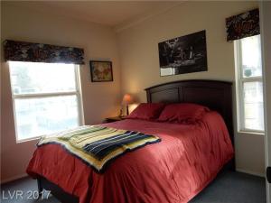 a bedroom with a bed with a red comforter and two windows at Southwest Retreat - Stylish Room with Queen Bed, Fast Wi-Fi & More! in Las Vegas