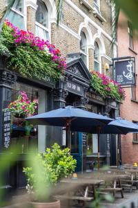 two tables with umbrellas in front of a building at Old Ship Inn Hackney in London