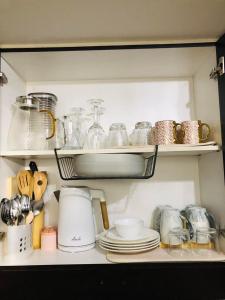 a kitchen shelf with plates and dishes on it at Chill Spot Staycation in Pasig in Manila