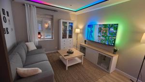 a living room with a couch and a flat screen tv at ARKANA, appartement avec 2 places de parking in Dole