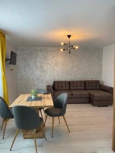 a living room with a couch and a table and chairs at Wonderland apartment in Bistriţa