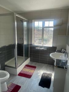 a bathroom with a shower and a toilet and a sink at OYO Baraka Edgware in Stone Grove