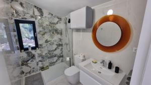 Un baño con lavabo, inodoro y espejo. en Robinson house DUJE, en Pašman