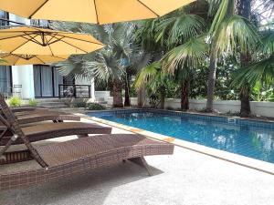 サムイ島にあるVilla LunaSole Samuiのスイミングプール(椅子、パラソル、木付)