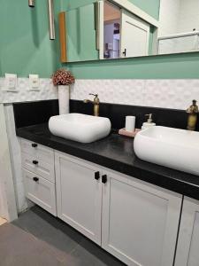 un bagno con due lavandini e uno specchio di Casa Ideal e Confortável a Sinop