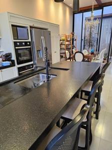 una cucina con bancone, lavandino e sedie di Casa Ideal e Confortável a Sinop