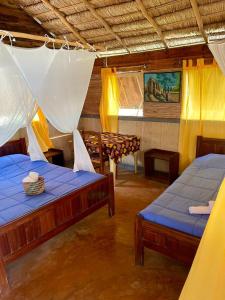 a room with two beds and a table at Hôtel Safari Vezo Anakao in Anakao