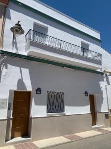 a white building with a balcony and a light at Apartamentos ANDASOL in Chipiona