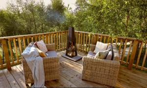a deck with two wicker chairs and a fireplace at Yurtshire Eavestone Lake - Willow in Ripon
