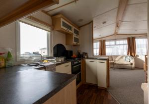 a kitchen with a counter top and a living room at Carnaby Holiday Caravan, West Sands, Selsey in Selsey