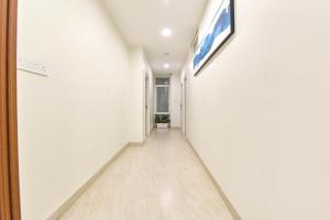 a hallway with white walls and wooden floors and a painting on the wall at FabHotel Rex in Indore