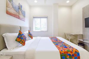 a white bedroom with a large bed with colorful pillows at FabHotel Rex in Indore