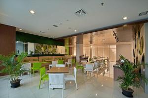 ein Restaurant mit Tischen, Stühlen und Pflanzen in der Unterkunft Whiz Prime Hotel Pajajaran Bogor in Bogor