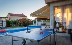 Una mesa de ping pong en un patio junto a una piscina. en Stunning Home In Vrsi With Sauna, en Vrsi