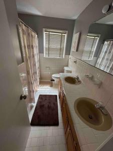 a bathroom with two sinks and a toilet and a mirror at University Cozy Escape in Huntsville +10 photos