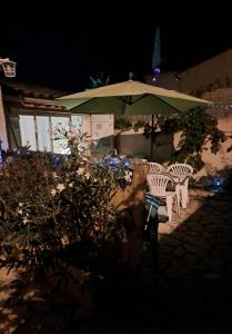 a table and chairs under an umbrella at night at Les Loulous in Ceyreste