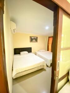 two beds in a room with a door open at Wayan Gunawan Homestay in Gianyar +5 photos