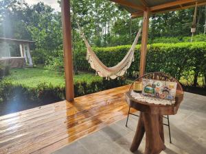 a hammock on a porch with a table and a chair at Romantic Cabin in the Forest, Valle Azul, Bungalows Tulipanes CR in San Ramón