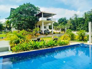 a villa with a swimming pool in front of a house at Rock View Inn in Padukka