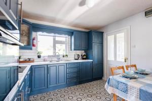 a blue kitchen with a sink and a table at Moneydarragh Cottage with uninterrupted mountain and sea views- Hot tub available for hire in Annalong