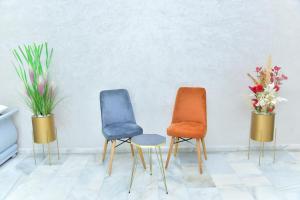 three chairs in a room with flowers in vases at Luxueux Appartement Parc Champs de Cours avec Wifi Fibre 200 Mo in Fès