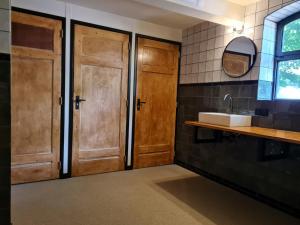 a bathroom with wooden doors and a sink at Bell Tent in een Voedselbos in Nederweert-Eind