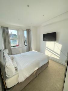 a white bedroom with a large bed and a flat screen tv at Modern Double Bedroom with Marble private bathroom in Edgware