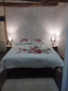 a bedroom with a large bed with two lamps at Le gîte du courtil in Tressé