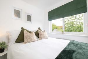 a bedroom with a white bed with pillows and a window at Langley House, 5 bed, all doubles with Smart TV fully equipped kitchen and spacious with private parking INVOICES and REDUCED RATES only available through Langley Cottages and Apartment IDEAL FOR TRADES in Dundee