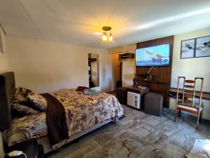 a bedroom with a bed and a flat screen tv at Monte Verde Inn Suítes com Hidromassagem dupla in Monte Verde