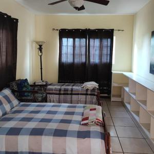 een slaapkamer met twee bedden en een plafondventilator bij J's Oasis in Nevis