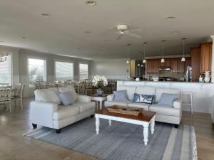 a living room with two couches and a kitchen at Most Requested 16 Br Oceanfront Home in Holden Beach in Holden Beach